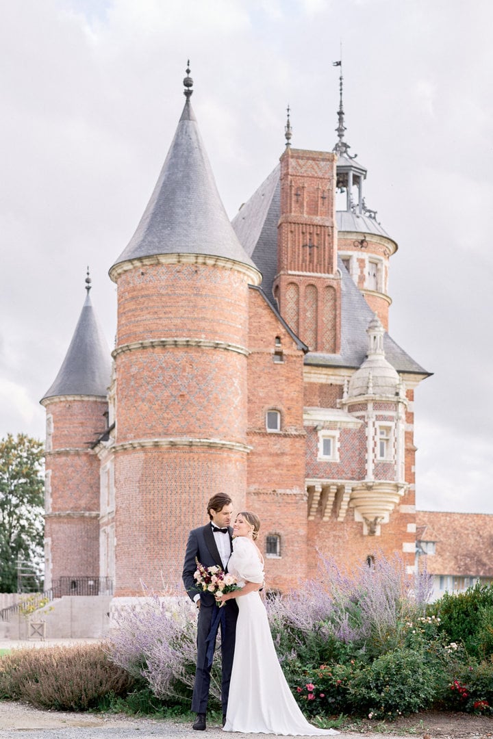 château mariage avec mariés devant heureux câlin photographie de mariage couleurs douces
